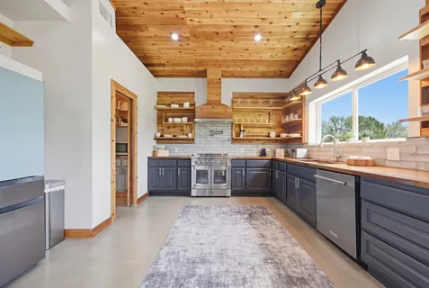 a large kitchen with stainless steel appliances granite countertop a sink and cabinets