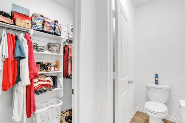 a view of walk in closet with clothes shoes and a painting on the wall