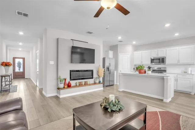 a living room with stainless steel appliances kitchen island furniture and a fireplace
