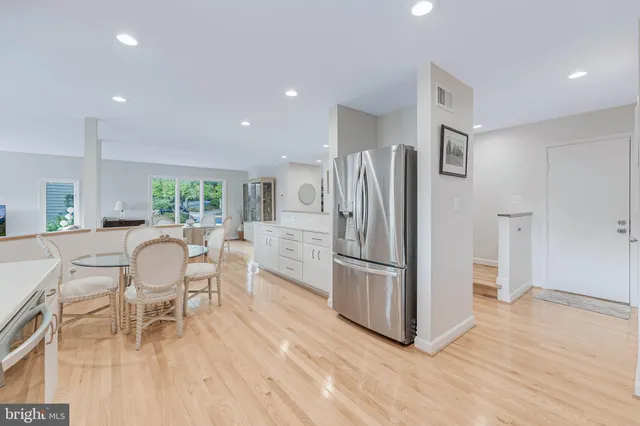 a kitchen with stainless steel appliances a dining table chairs refrigerator and sink