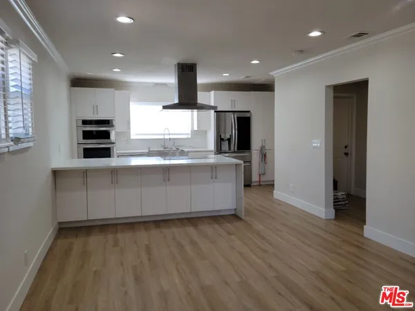 a large kitchen with stainless steel appliances a large counter top a stove a sink and a refrigerator