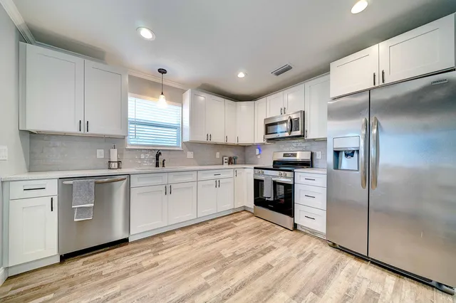 a kitchen with granite countertop white cabinets and stainless steel appliances