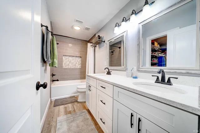 a spacious bathroom with a double vanity sink a mirror and a bathtub