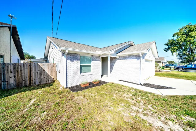 a view of a house with backyard and wooden fence