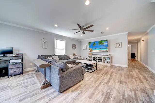 a living room with furniture a wooden floor and a ceiling fan