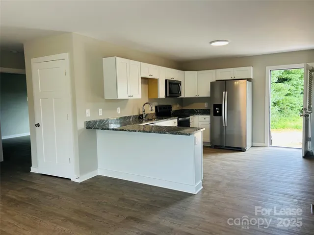 a kitchen with granite countertop a refrigerator and a stove top oven