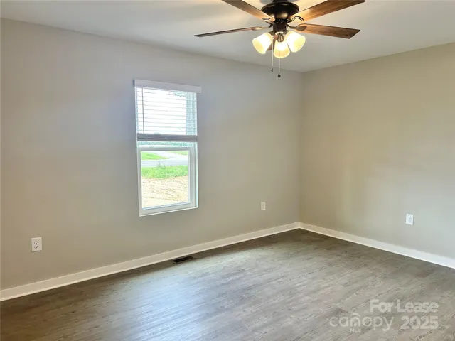 an empty room with a window and a chandelier fan