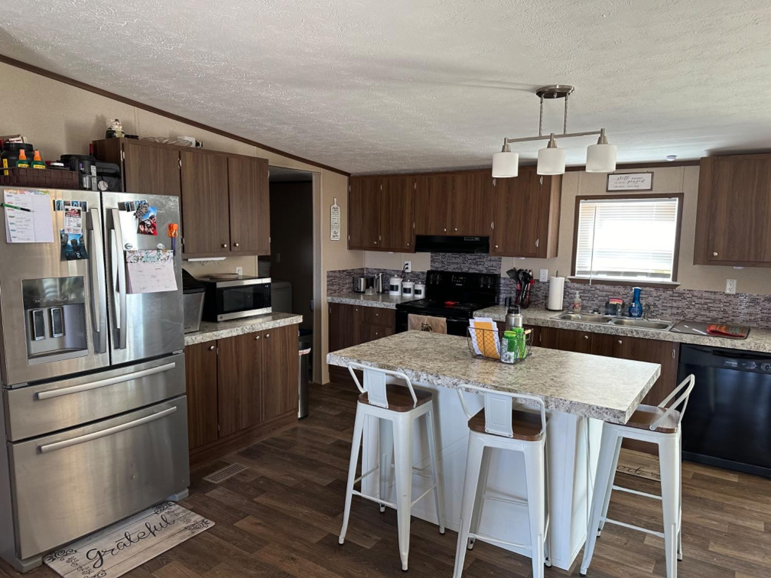 760 Highway 82 Ralls, TX 79357 - Photo 13 of 25 a kitchen with granite countertop a refrigerator a stove a sink a dining table and chairs with wooden floor