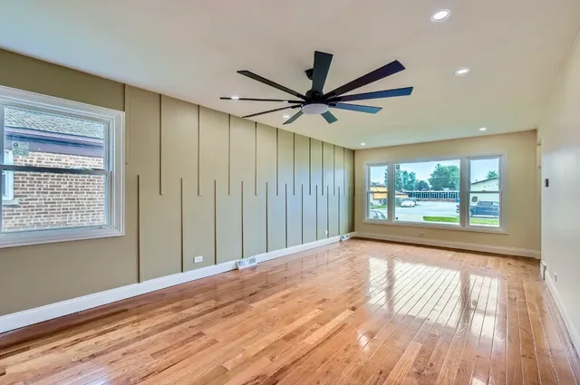 a view of n empty room with wooden floor and a window