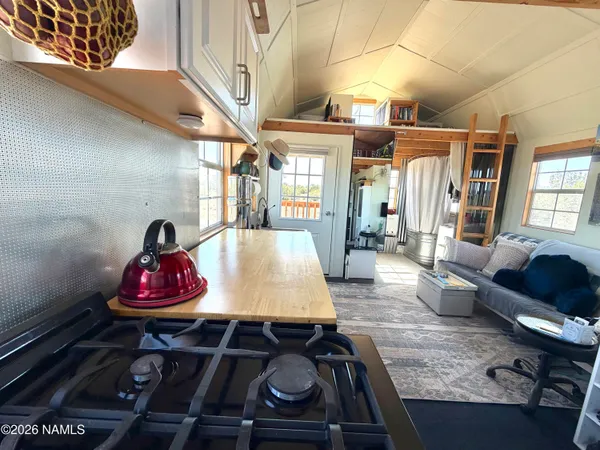 a kitchen with a refrigerator a stove a sink and a dining table with wooden floor