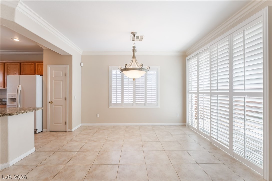 10481 Riverside Park Avenue Las Vegas, NV 89135 - Photo 10 of 51 Unfurnished dining area featuring crown molding and light tile patterned floors