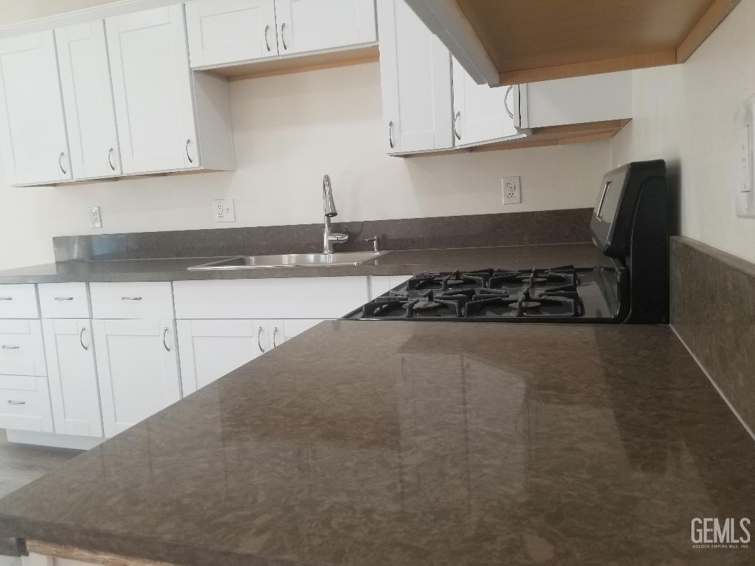 Undisclosed Address Delano, CA 93215 - Photo 5 of 10 a kitchen with stainless steel appliances granite countertop a stove a sink dishwasher and cabinets with wooden floor