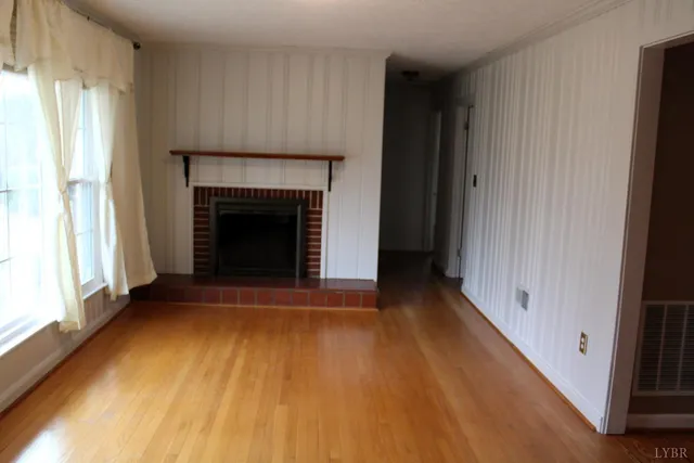 a view of an empty room with window and fire place