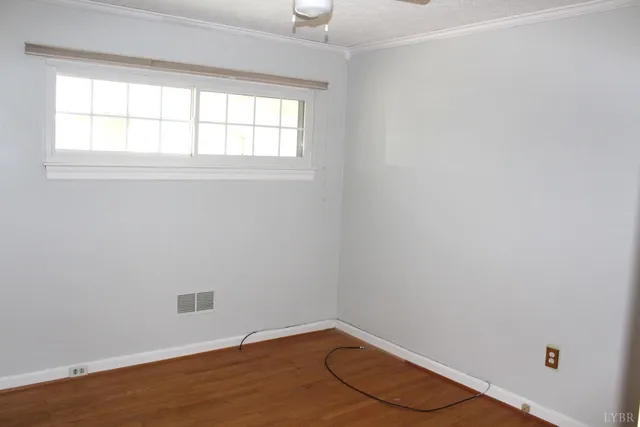 a view of an empty room with wooden floor and closet