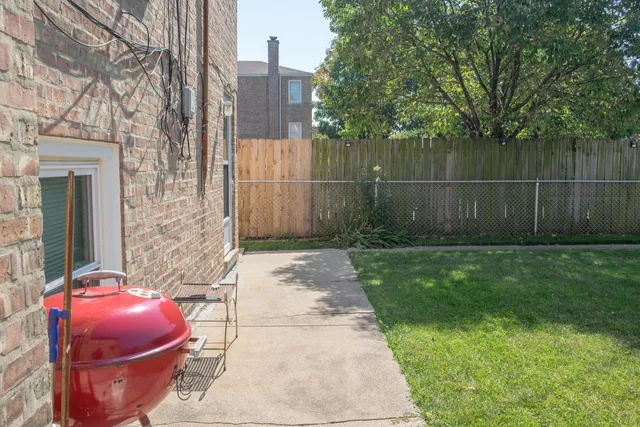 a view of a chair and table in backyard of the house