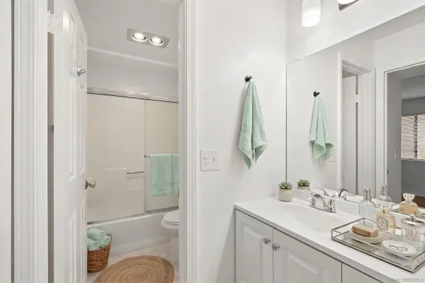a bathroom with a granite countertop sink vanity mirror and shower