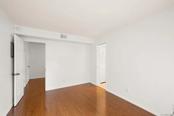 a view of an empty room with wooden floor and closet