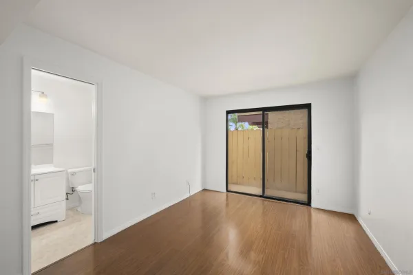 a view of an empty room with wooden floor and a bathroom