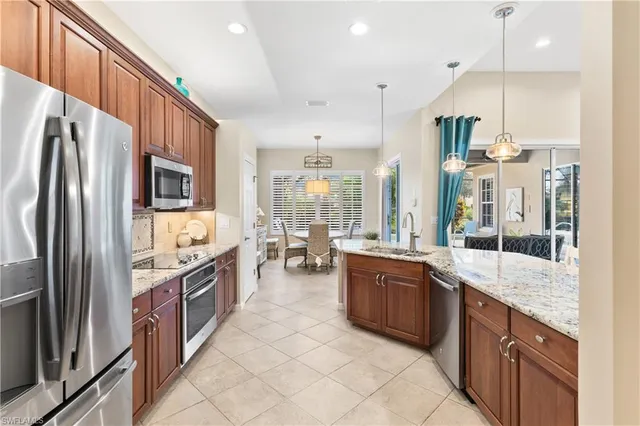a large kitchen with granite countertop a large counter top stainless steel appliances and cabinets