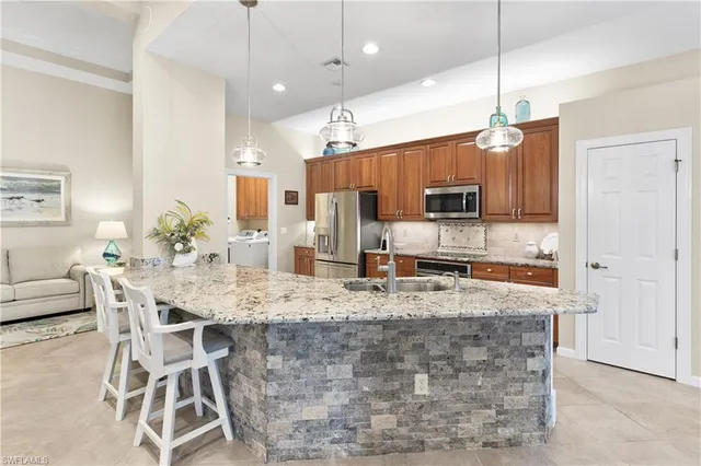 a kitchen with stainless steel appliances kitchen island granite countertop a stove a refrigerator a sink a dining table and chairs with wooden floor