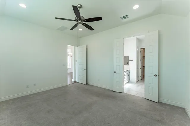 an empty room with ceiling fan and windows