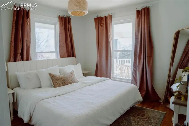 a bedroom with a bed and a large mirror next to a window