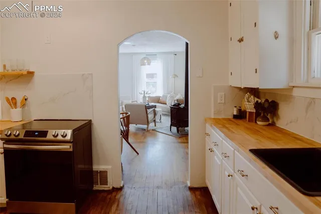 a kitchen with a stove and wooden floor
