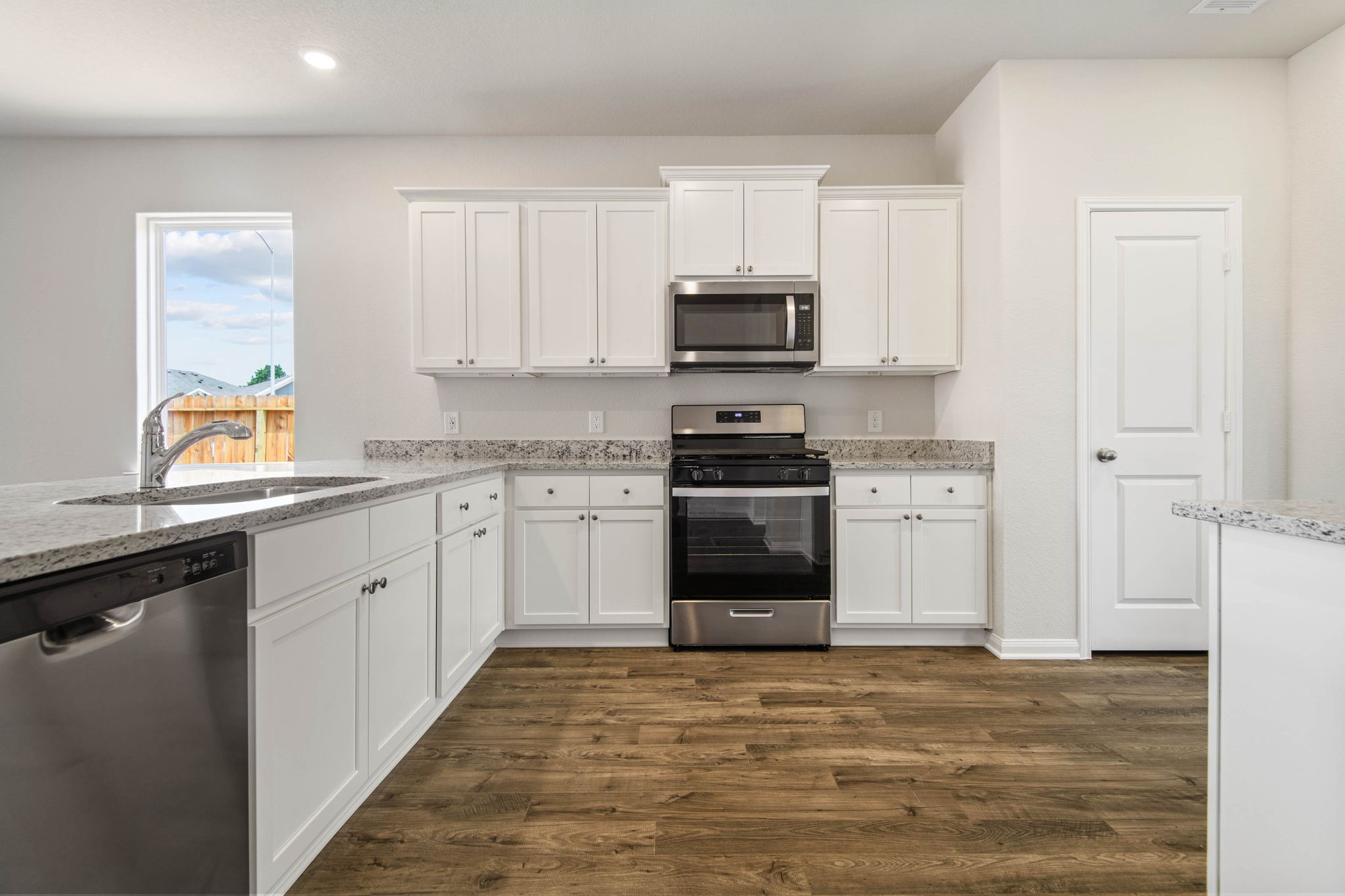 708 Jasmine Ridge Lane Waller, TX 77484 - Photo 4 of 12 a kitchen with stainless steel appliances a sink dishwasher a stove top oven a refrigerator with grey cabinets and wooden floor