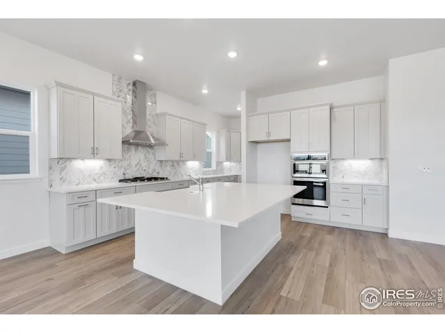 a kitchen with stainless steel appliances kitchen island granite countertop a sink a stove a refrigerator and white cabinets