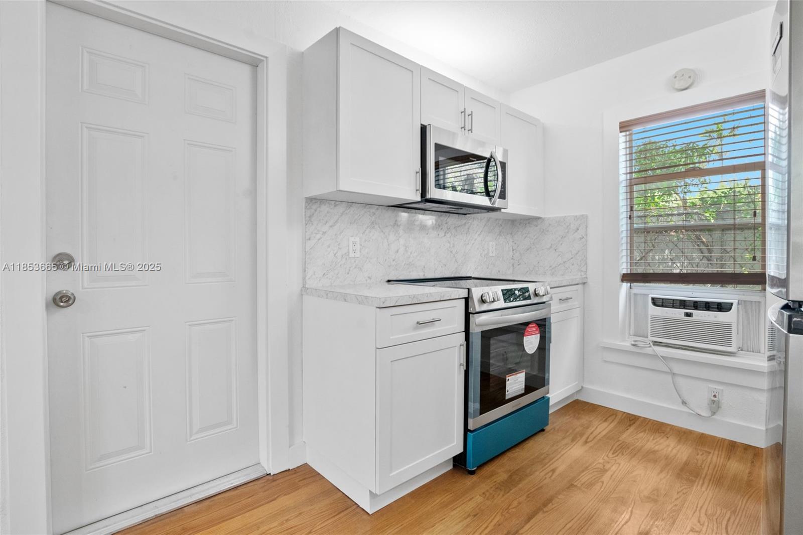 1721 Southwest 21st Terrace, Unit 1719 Miami, FL 33145 - Photo 3 of 25 a kitchen with stainless steel appliances white cabinets and a wooden floor