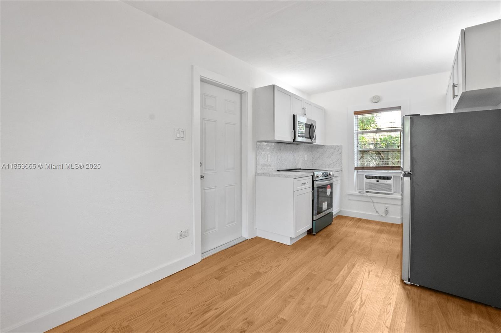1721 Southwest 21st Terrace, Unit 1719 Miami, FL 33145 - Photo 6 of 25 a kitchen with a refrigerator a stove top oven and white cabinets
