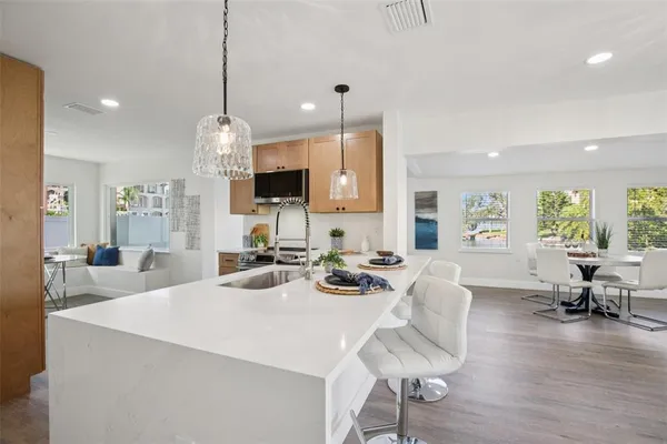 a view of a dining room and livingroom with furniture wooden floor a chandelier