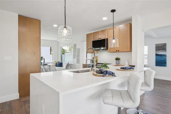 a kitchen with microwave a sink and chairs