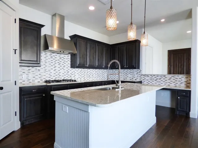 a kitchen with stainless steel appliances granite countertop a sink a microwave oven and a center island with wooden floor