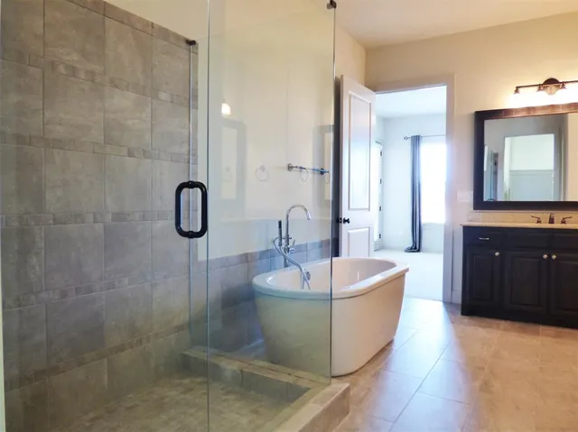 a spacious bathroom with a tub sink and mirror