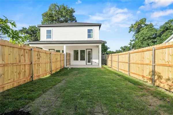 a view of backyard of house with wooden fence
