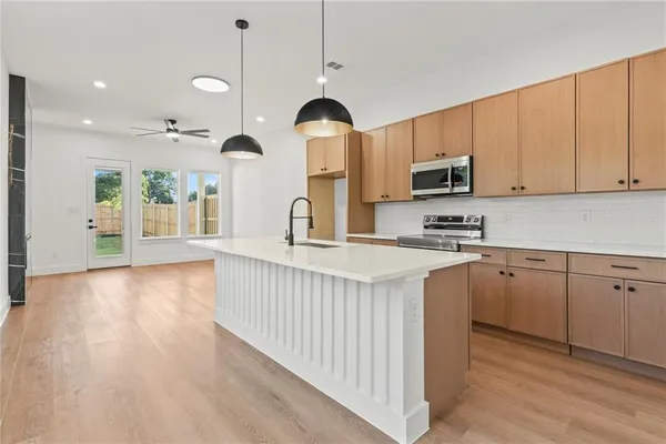 a kitchen with stainless steel appliances granite countertop a stove a sink and a wooden floors