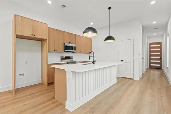 a kitchen with kitchen island a refrigerator a sink and wooden floor