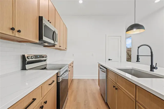 a kitchen with stainless steel appliances granite countertop a sink a stove and microwave with wooden floor