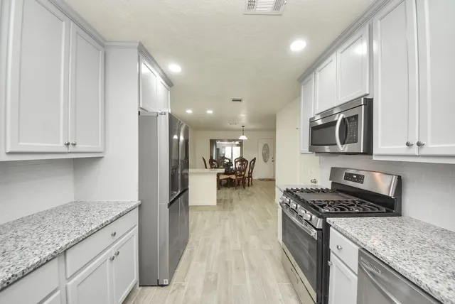 a kitchen with stainless steel appliances granite countertop a stove a sink and a microwave