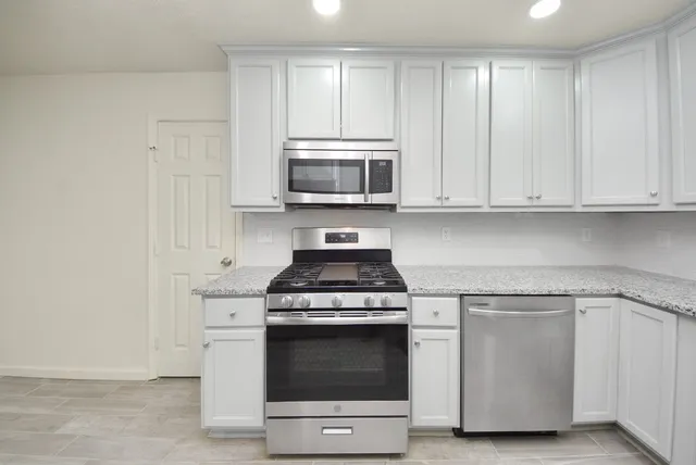a kitchen with granite countertop white cabinets and stainless steel appliances