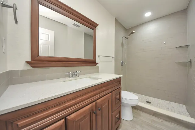 a bathroom with a sink a toilet a mirror and shower
