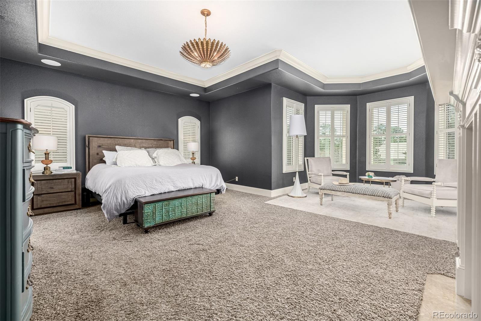 648 Ruby Trust Drive Castle Rock, CO 80108 - Photo 21 of 49 a spacious bedroom with a bed a chandelier and a large window