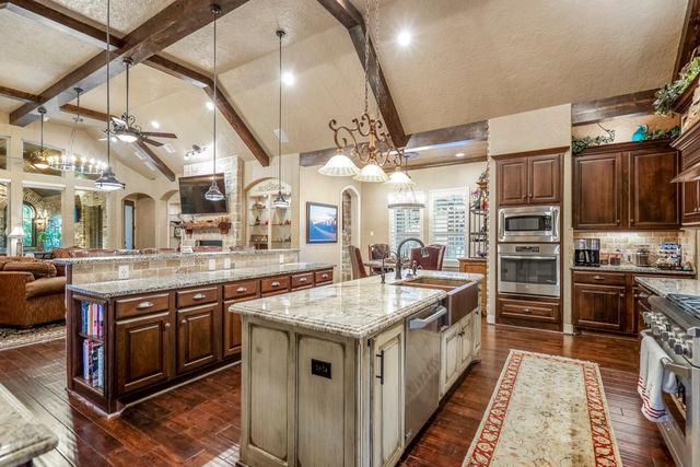 a kitchen with stainless steel appliances granite countertop a kitchen island a stove and a sink