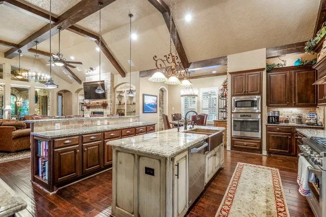 a kitchen with stainless steel appliances granite countertop a kitchen island a stove and a sink