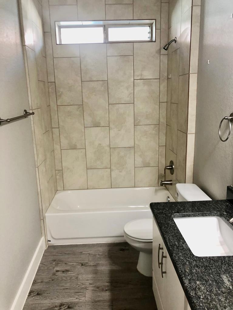 229 Riley Lane Fredericksburg, TX 78624 - Photo 16 of 16 a bathroom with a granite countertop bathtub sink vanity mirror and toilet