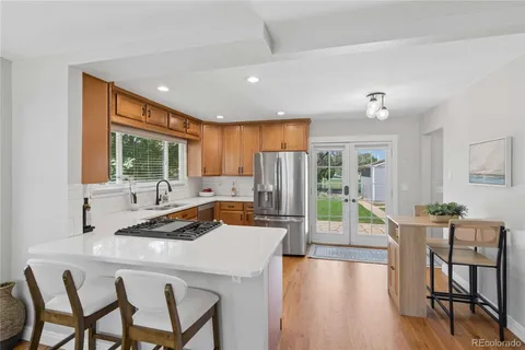 a kitchen with stainless steel appliances granite countertop a stove a refrigerator a kitchen island with chairs and wooden floor
