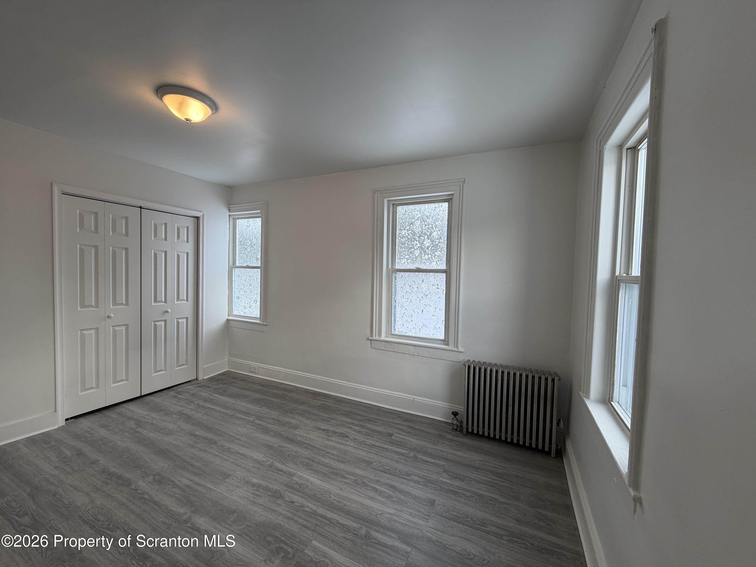 101 Clarkson Street, Unit 1 Jessup, PA 18434 - Photo 12 of 13 an empty room with wooden floor and windows