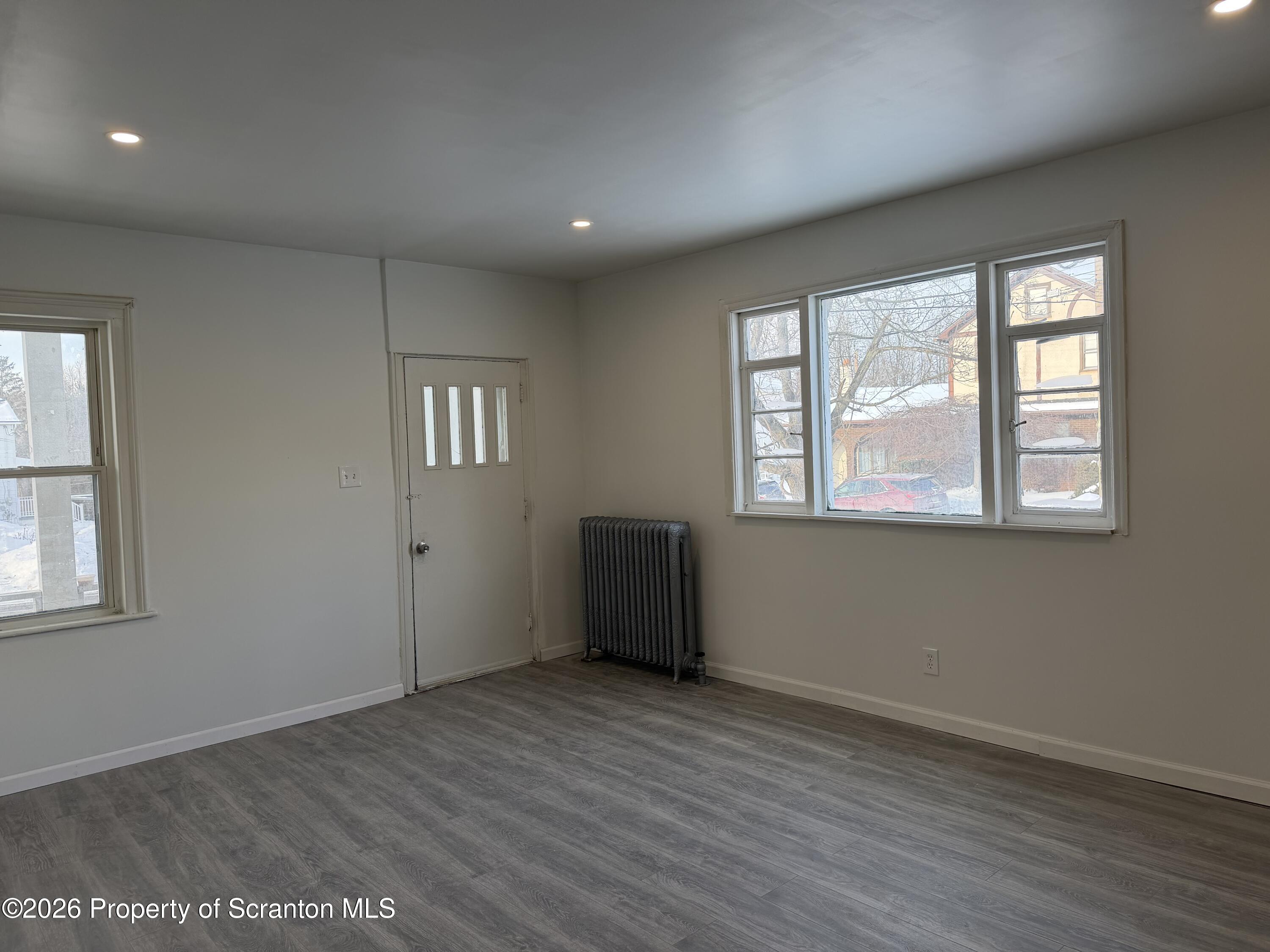 101 Clarkson Street, Unit 1 Jessup, PA 18434 - Photo 3 of 13 an empty room with wooden floor and windows