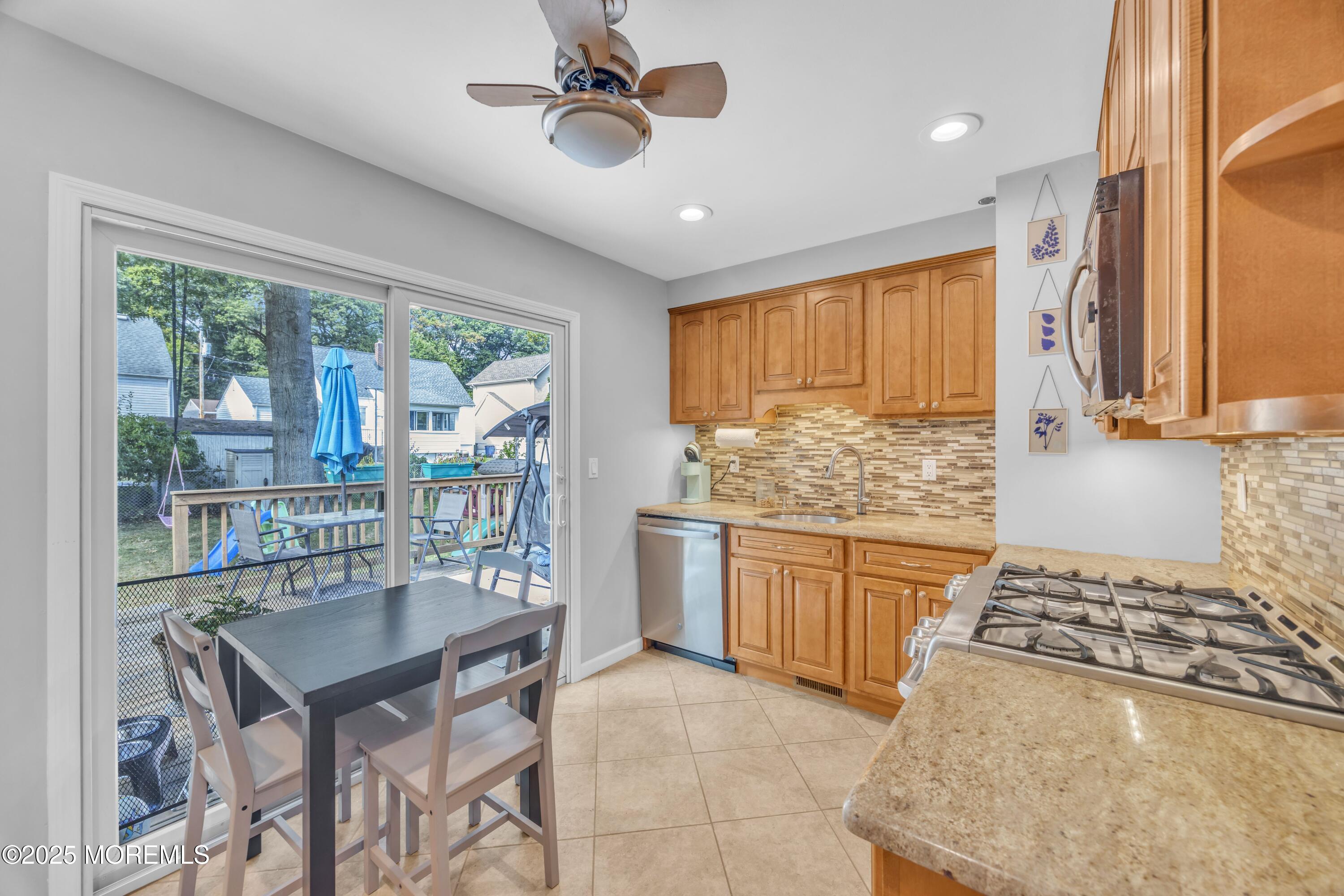 75 Ridgewood Road Clifton, NJ 07012 - Photo 8 of 41 a kitchen with a stove a sink dishwasher a dining table and chairs with wooden floor